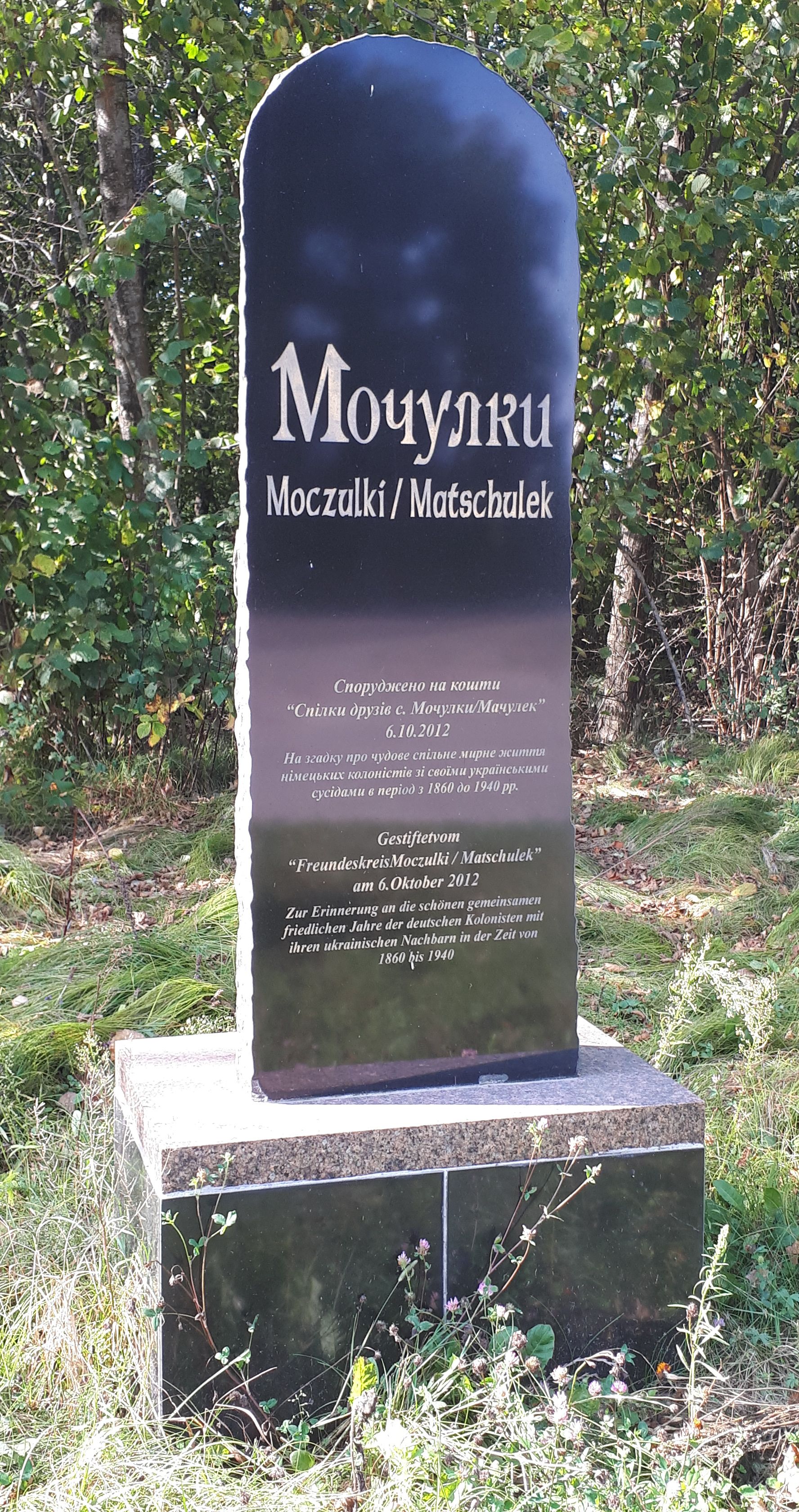 Erinnerungsschild am Eingang des Dorfes Motschulky, Rajon Riwne, Oblast Riwne, das von Mitgliedern der ukrainisch-deutschen Stiftung "Motschulky" im Jahr 2012 errichtet wurde